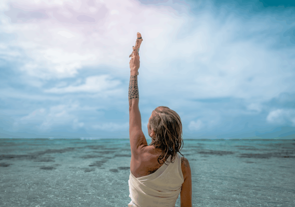 Lina Schneider am Meer mit erhobenem Arm, der Blick in die Weite – KAIMANA Audio Journey Selbstverbindung